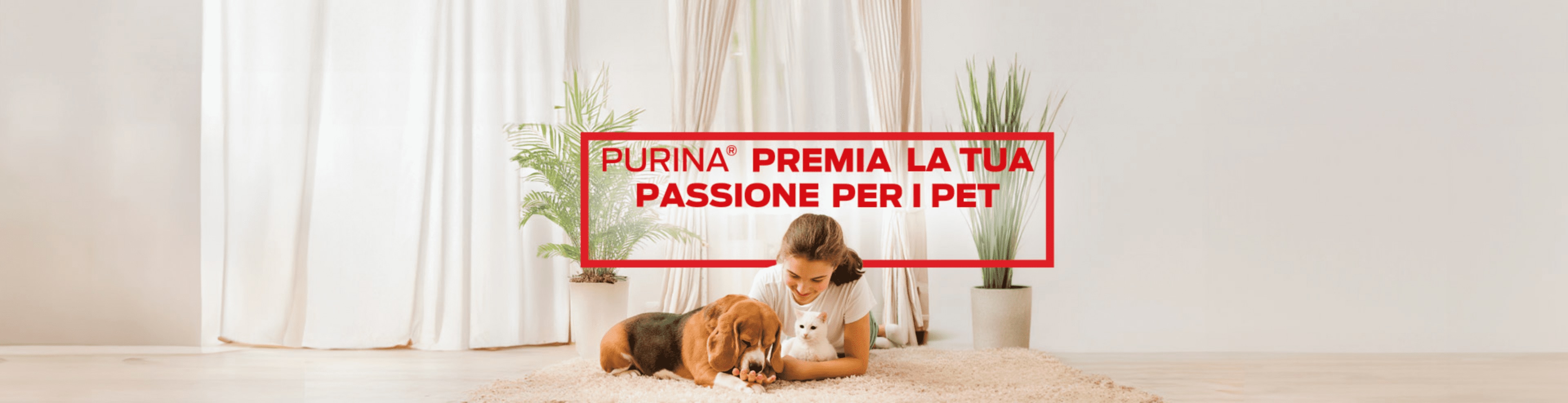 ragazza distesa su tappeto bianco con un cane e un gatto in braccio, sullo sfondo una tenda da salotto e due piante con vaso. Sopra di lei, il testo:'Purina premia la tua passione per i pet'